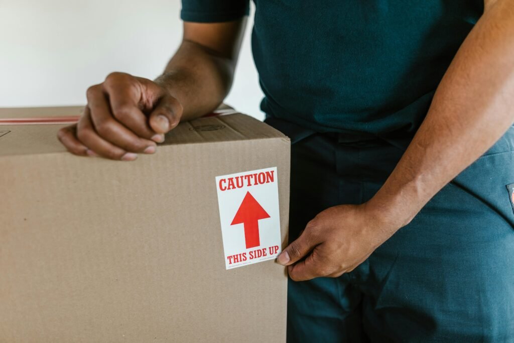 pexels-photo-7464731-7464731 A person handling a moving box with a 'caution this side up' label indoors.